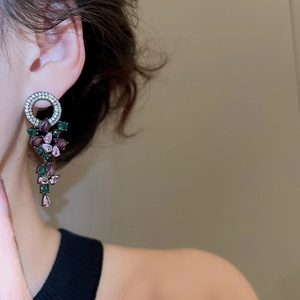 Detailed close-up of long tassel earrings with purple and green pear-cut gemstones