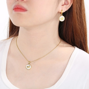 Close-up of a model wearing a gold necklace and earrings with round butterfly pendants