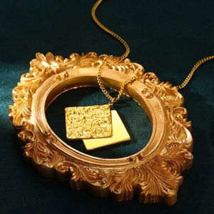 Close-up of gold layered square pendant necklace with irregular texture on vintage velvet