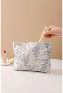 Close-up of a floral cosmetic bag showing hydrangea texture and a white woven label