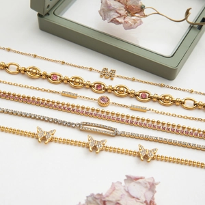 Detail view of gold-plated bracelets featuring zircon butterfly and letter charms on jewelry box