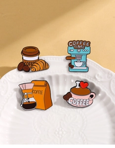 Macro detail of coffee enamel pin set including brewer and cup on vintage white plate