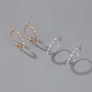 Detail view of gold and silver hoop earrings featuring marquise-cut zircon stones