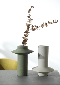 Detail of minimalist ceramic vases with matte spiral texture and geometric disc accents