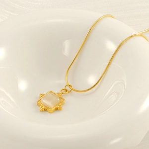 Collier chaîne serpent dorée avec pendentif pierre de lune carrée sur plat céramique