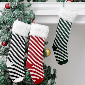 Three knitted Christmas stockings with striped patterns and plush cuffs on fireplace