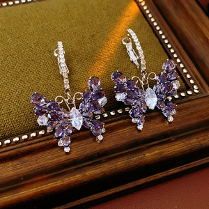Macro detail of silver butterfly earrings featuring purple pear-shaped zircon stones