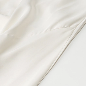 Detailed close-up showing the smooth satin texture and fine stitching of the white dress