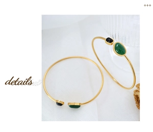 Close-up of gold slim bangles with oval green gemstone and vintage minimalist details