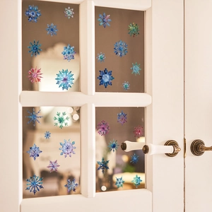 Watercolor snowflake window clings set in various colors on a white grid window glass