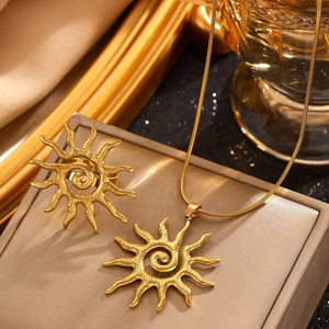 Detail of gold sunburst necklace and ring set on jewelry cushion with textured finish