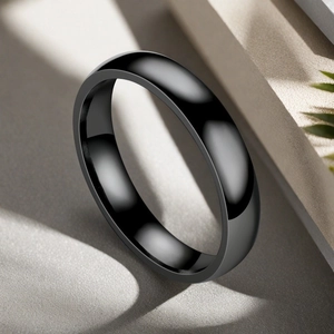 Close-up of a polished black stainless steel ring with a smooth mirror finish and domed design