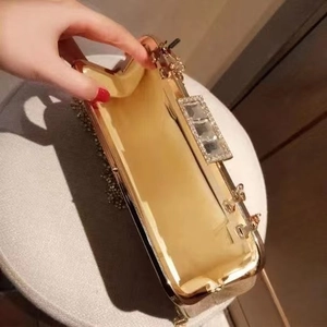 Golden evening clutch bag with crystal buckle and satin lining shown from an open angle