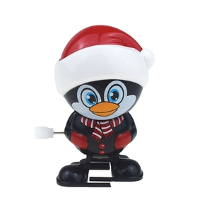 Close-up of wind-up penguin toy with red Christmas hat and scarf on white background
