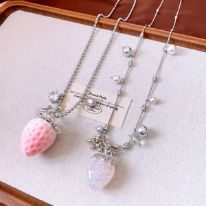 Close-up of strawberry pendant necklaces with pearls and silver chain on a tray