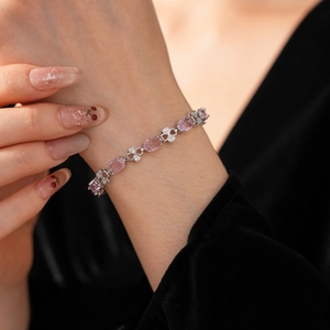 Close-up of vintage silver bracelet with pink zircon stones and clover charms on wrist