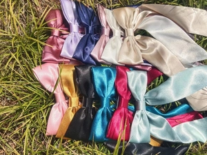 Close-up of colorful silk satin hair ribbons in thirteen vibrant shades on green grass