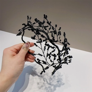 Detailed view of handmade black beaded headband with elegant branch-like crystal design
