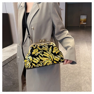 Close-up of vintage sequin shell bag with gold pattern worn by model in grey suit
