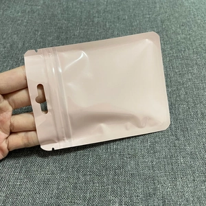 Close-up of pink stand-up zip lock jewelry bag with handle hole on gray fabric background