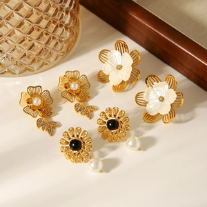 Golden stainless steel flower earrings set with pearls, shells and crystals on a tray