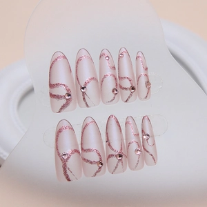 Almond press-on nails with rose gold glitter swirls and rhinestones on matte base