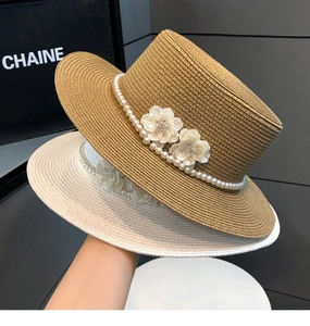 Detail of flat top straw hats with elegant pearl chains and delicate flower ornaments
