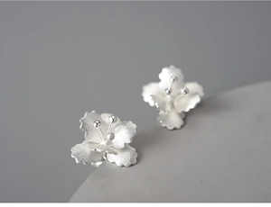 Macro shot of 925 sterling silver flower stud earrings with brushed metallic texture