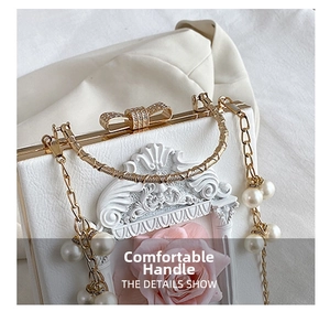Detail of white textured bag with floral relief, pearl chain, and diamond bow clasp