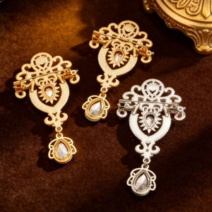 Macro detail of vintage hollow-out brooches with teardrop crystal pendants and safety pins