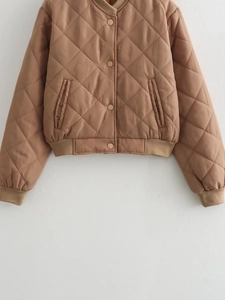 Close-up of brown diamond-quilted bomber jacket with snap buttons and ribbed cuffs