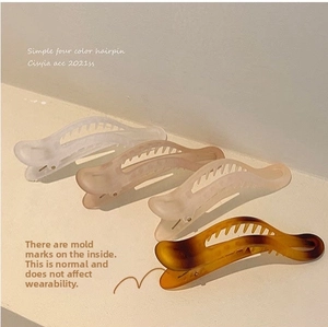 Close-up of four-color matte resin hair clips with smooth curved shell and inner teeth
