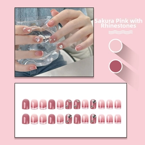 Detail of cherry pink gradient press-on nails with sparkling rhinestones and French tips