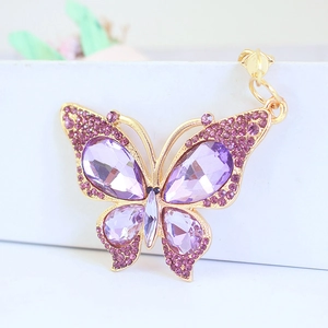 Gold butterfly keychain with purple crystals and rhinestones on white background