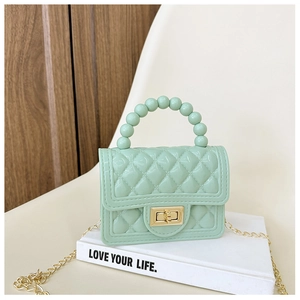 Light green jelly bag with pearl handle and gold chain strap on a white chair