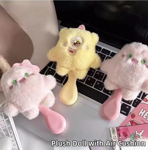 Detail of plush monster hairbrushes in pink and yellow on a laptop keyboard