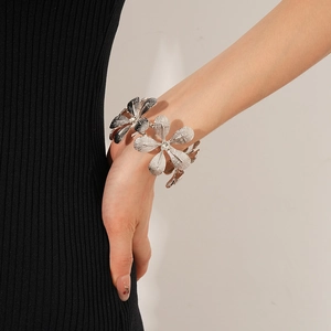 Detailaufnahme eines silbernen Blumenarmbands mit gewebter Metallstruktur und Kristallen