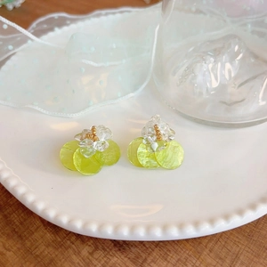 Detail view of lime green shell flower stud earrings with sparkling crystal accents