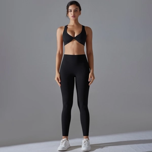 Detail of high-waisted yoga leggings and cross V-neck sports bra in black fabric