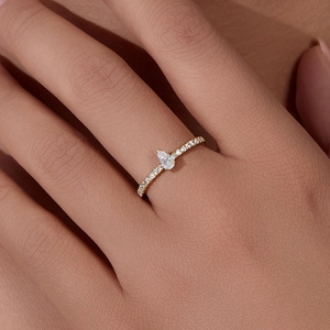 Elegant gold pear-cut zircon ring with pavé stones on finger in minimalist style