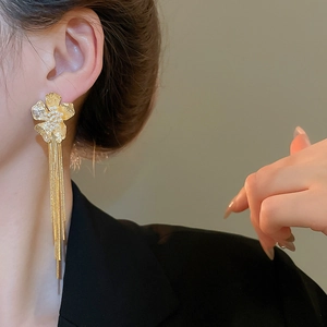 Detailed close-up of 18k gold-plated flower earrings with long fringe on model