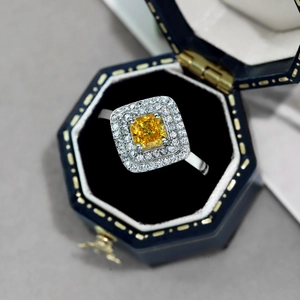 Detail of yellow square zircon ring with double halo setting in a blue jewelry box