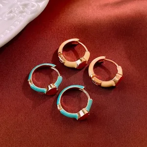 Vintage enamel heart huggie earrings in beige and turquoise colors on red silk fabric