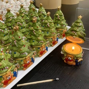 Detailed view of an open Christmas tree ceramic jewelry box with a lit scented candle inside