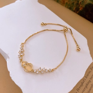 Macro shot of gold zircon gourd charm bracelet with bowknot and adjustable chain detail