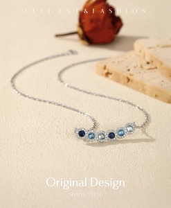 Macro shot of silver necklace with gradient blue and clear crystals on textured background