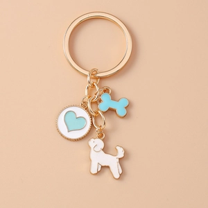 Detail of gold keychain with light blue heart, bone, and cute white puppy enamel charms