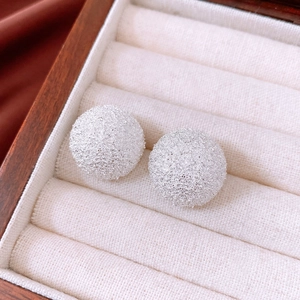 Macro shot of silver ball stud earrings featuring a frosted matte sand-blasted texture