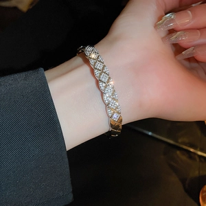 Close-up of zircon grid cross bracelet in silver finish on woman wrist with luxury texture