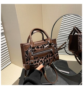 Detalle de bolso de leopardo con costuras de cuero marrón y acentos de cremallera metálica